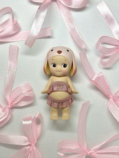 there is a small doll with pink ribbon around it