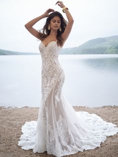 a woman is posing on the beach wearing a wedding dress with an open - back