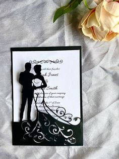 a paper cut silhouette of a bride and groom on their wedding day, next to a flower