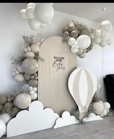 balloons are hanging from the ceiling in front of a wall with white and silver decorations