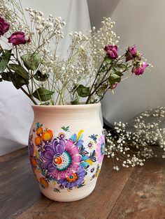 a vase with flowers painted on it sitting on a table