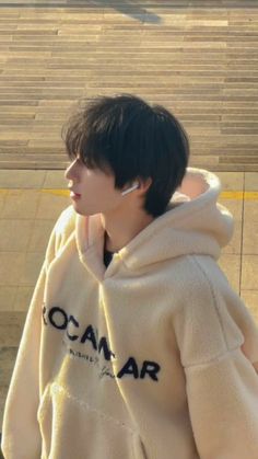 a young man with ear buds on his ears is standing in front of some steps