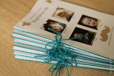 an open book tied up with twine on top of a wooden table next to pictures