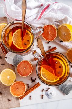 two glasses of tea with orange slices and cinnamon sticks