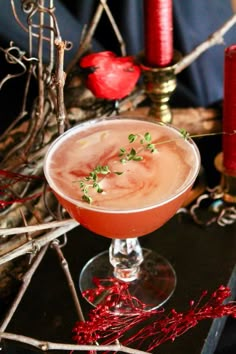 a drink sitting on top of a table next to some candles and red tinsel