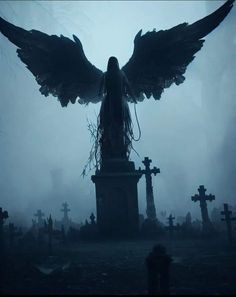 an angel statue surrounded by tombstones and crosses in a cemetery on a foggy day