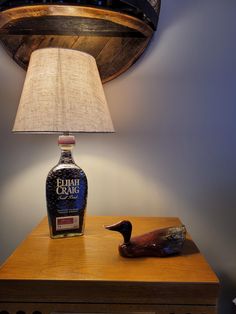 a duck lamp sitting on top of a wooden table next to a bottle of alcohol