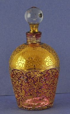 a gold and red glass bottle sitting on top of a table