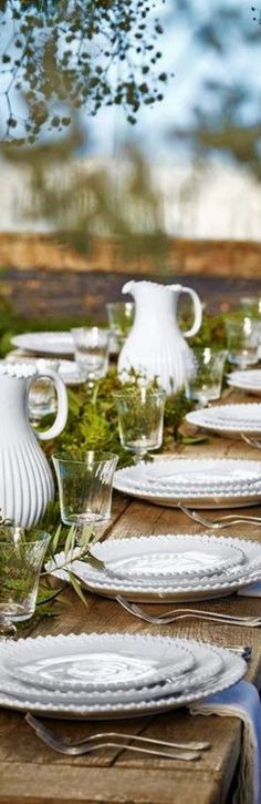 there are many plates and pitchers on the table set for an outdoor dinner or party