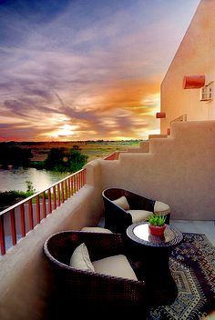 two wicker chairs sitting on top of a balcony