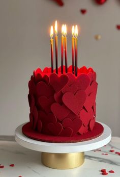 a red heart shaped cake with candles in the middle