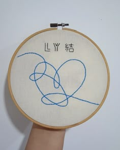 a hand is holding up a embroidery hoop with an image of two hearts on it