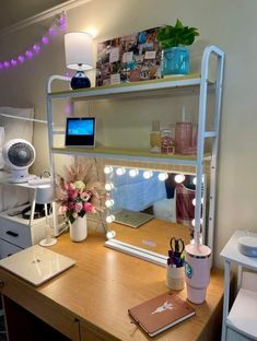 a desk with a laptop, mirror and lights on it in front of a window