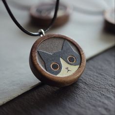 a wooden necklace with a black and white cat on it