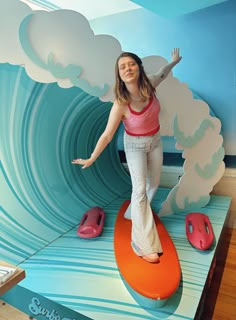 a woman is standing on top of a surfboard