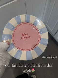 a person holding up a plate with the words bon appetit written on it