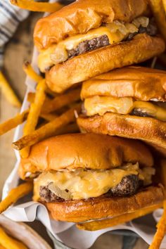 three cheeseburgers and french fries on a tray