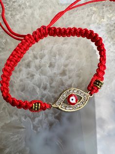 a red string bracelet with an evil eye charm