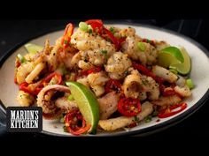 a white plate topped with shrimp and veggies next to a lime wedge on top of a table