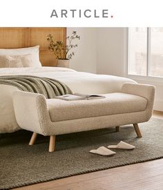 a bed sitting on top of a wooden floor next to a white blanket and pillows