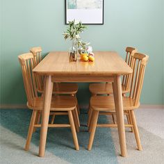 a wooden table with four chairs and a vase filled with flowers on top of it