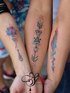 two girls holding hands with tattoos on their arms and armbands in the shape of arrows