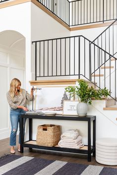 a woman standing in front of a staircase next to a table with towels on it