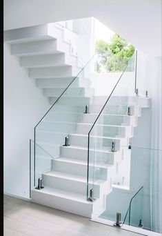 a white staircase with glass railing and handrail