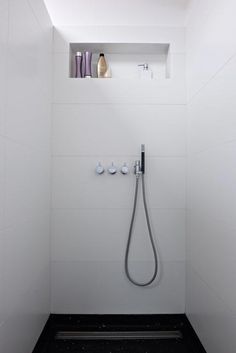 the shower head is mounted to the wall in this modern bathroom with white walls and black flooring