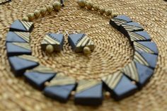 a close up of a necklace and earring on a woven place mat with beads