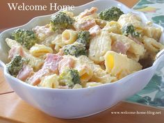 a bowl filled with pasta and broccoli sitting on top of a wooden table