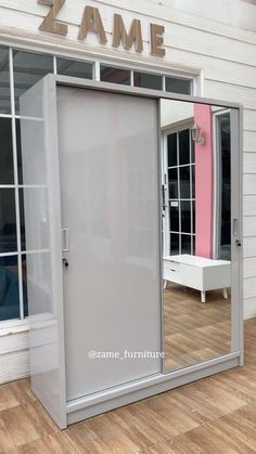 a large mirror sitting on top of a wooden floor next to a wall mounted cabinet