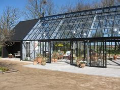 a glass house with potted plants in the front