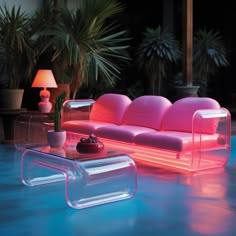 an illuminated couch and coffee table in the middle of a room with potted plants