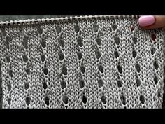 someone is holding up the edge of a knitted blanket with holes in it and their thumbnails are visible