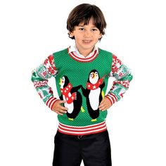 a young boy in a penguin christmas sweater standing with his hands on his hips and smiling at the camera