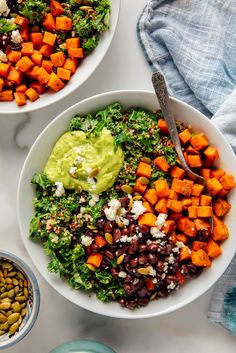 two bowls filled with vegetables, beans and guacamole on top of a table