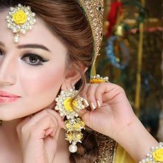 a woman in a bridal outfit with yellow flowers on her head and jewelry around her neck