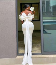 a woman in a white dress standing on steps with her back turned to the camera