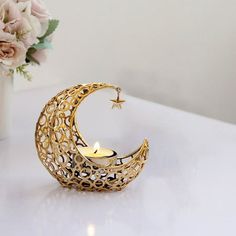 a gold crescent candle holder with a star on the top and a flower vase in the background