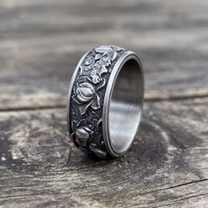 a wedding ring with flowers and leaves on the inside is sitting on a wooden surface