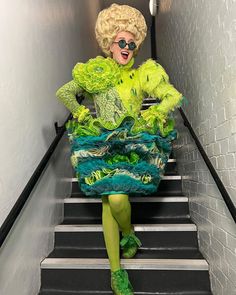 a woman dressed in green and yellow sitting on some stairs