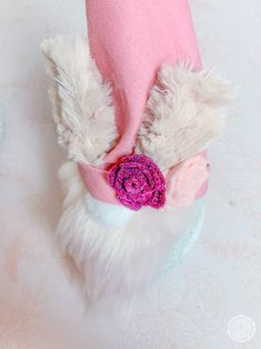 a stuffed animal wearing a pink hat with a flower on it's head and ears