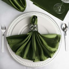 a place setting with green napkins and silverware