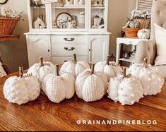 white pumpkins are sitting on a table in front of a china cabinet