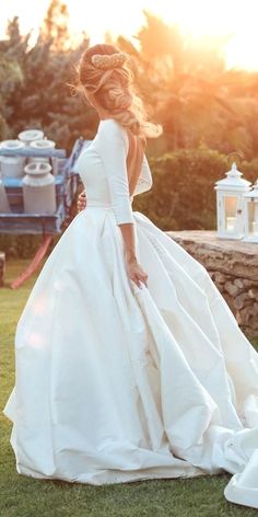 a woman in a white wedding dress standing on the grass