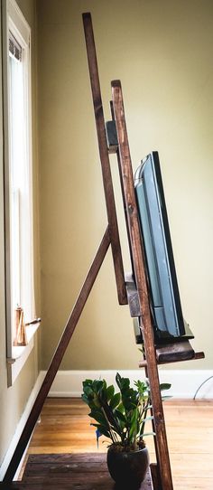 a wooden ladder holding a television and potted plant