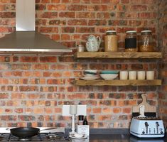 a stove top oven sitting inside of a kitchen next to a wall covered in shelves