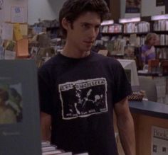 the young man is standing in front of books