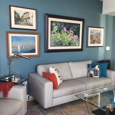 a living room with blue walls and pictures on the wall above the white couches